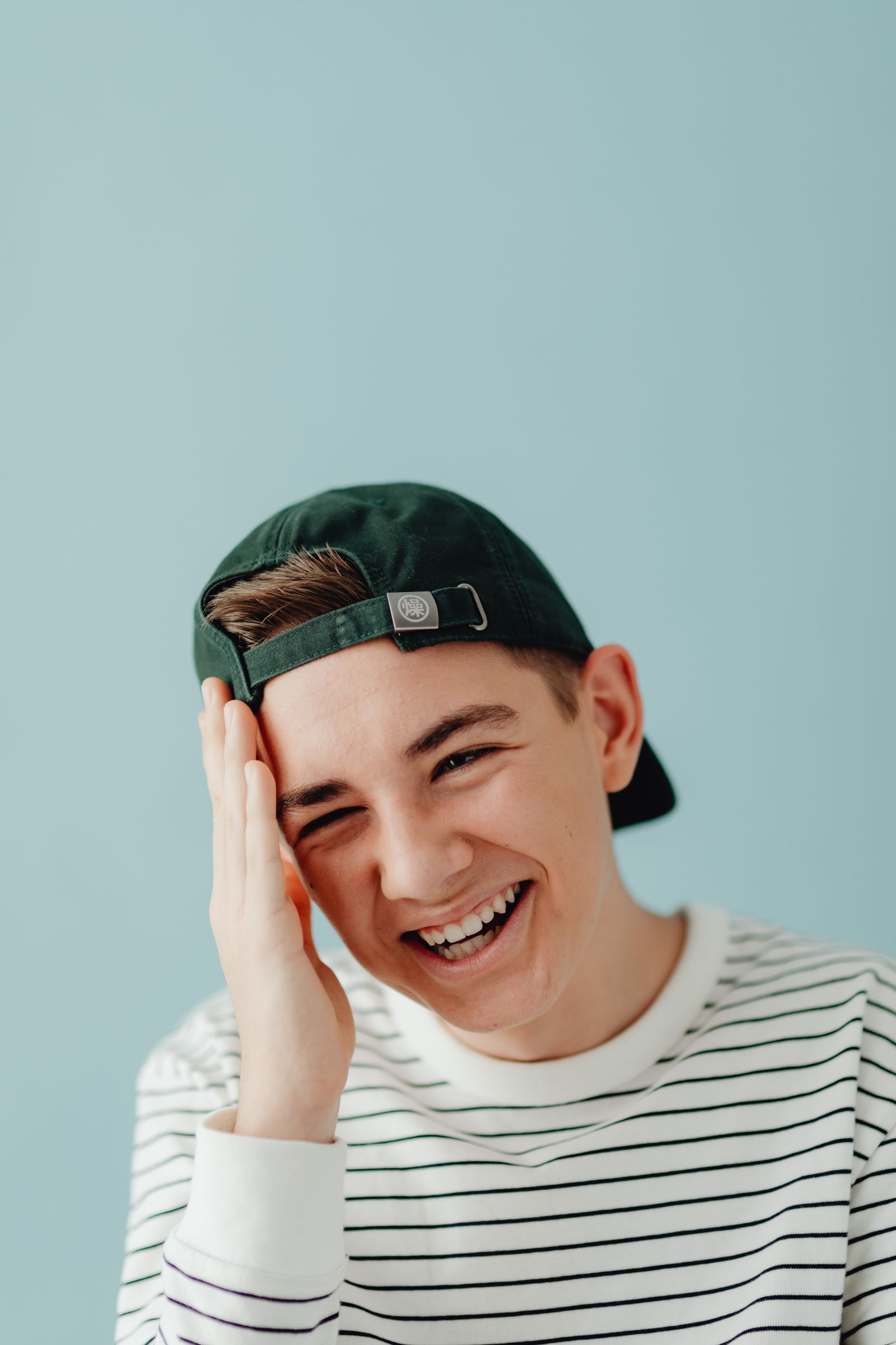 Teen boy laughing against a blue backdrop