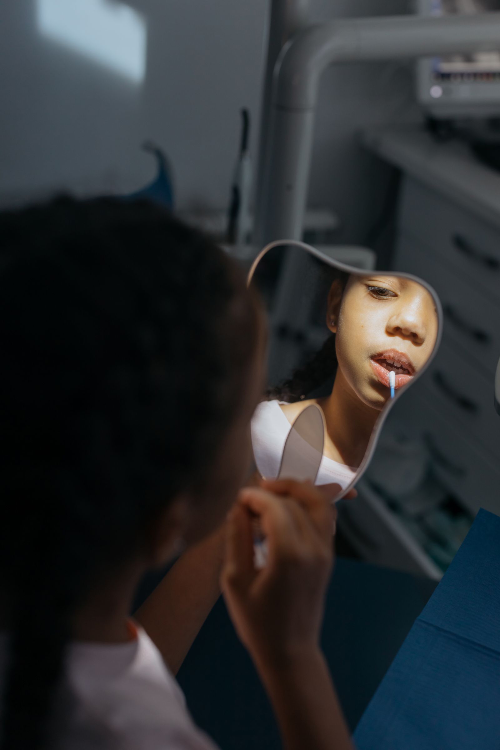 Child looking at her teeth in a hand mirror during a checkup